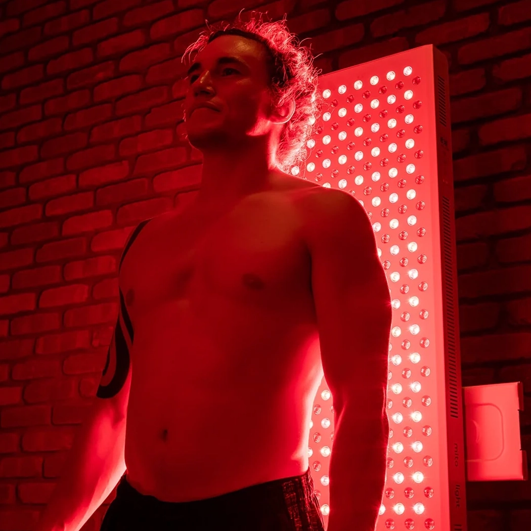 Person receiving Red Light Therapy from large, glowing MitoPro Mega panels in a modern clinic